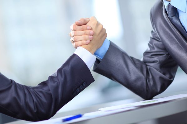Two businessmen press hands each other on a forward background