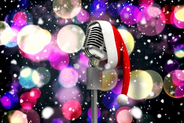 Composite image of microphone with santa hat against twinkling yellow and purple lights