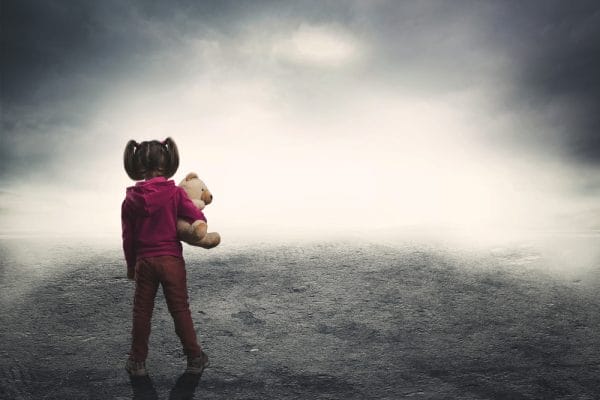 Little girl with toy bear in the darkness